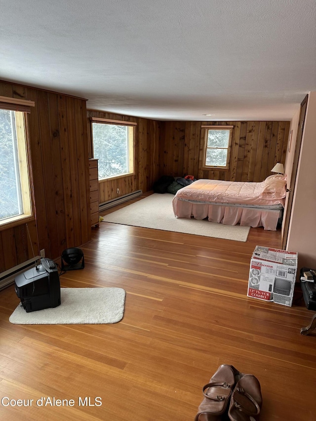366 Yukon Rd, Bonners Ferry, ID 83805 - bedroom featuring baseboard heating, wooden walls, multiple windows, and wood finished floors