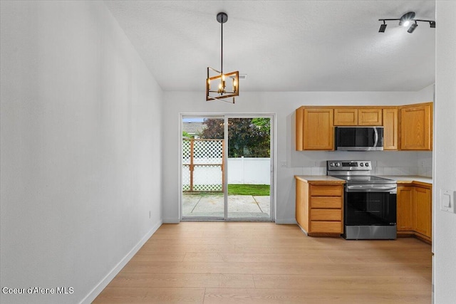 1374 W Timor Ave, Coeur Dalene, ID 83815 - kitchen with stainless steel appliances, light countertops, light wood finished floors, a chandelier, and baseboards