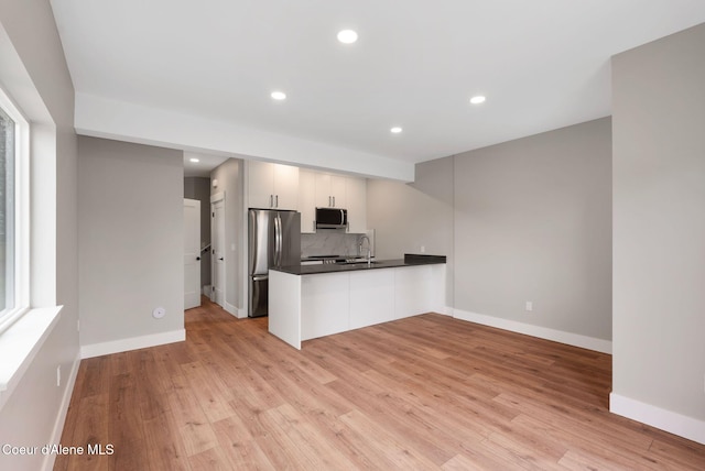 1682 Onyx Ct 1670, 1674 1678, Sandpoint, ID 83864 - kitchen with stainless steel appliances, a peninsula, dark countertops, backsplash, and light wood-style floors
