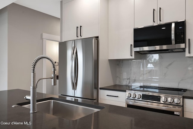 1682 Onyx Ct 1670, 1674 1678, Sandpoint, ID 83864 - kitchen featuring stainless steel appliances, dark countertops, a sink, decorative backsplash, and white cabinetry
