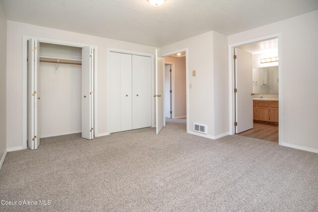 1130 E Timber Ln # 7, Coeur Dalene, ID 83815 - unfurnished bedroom with multiple closets, light colored carpet, baseboards, and a sink