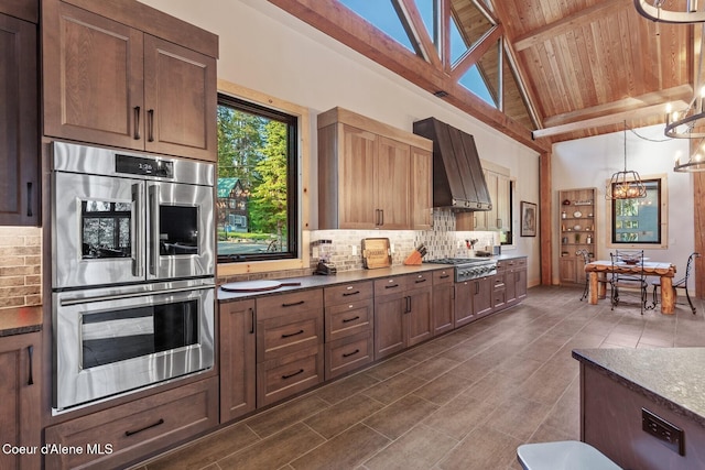 14318 N Waters Edge Ct, Hayden, ID 83835 - kitchen featuring appliances with stainless steel finishes, backsplash, a chandelier, wooden ceiling with exposed beams, and wall chimney exhaust hood