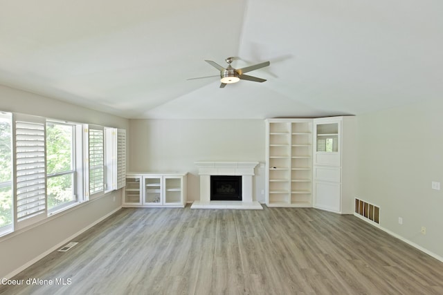 8485 N Audubon Dr, Hayden, ID 83835 - unfurnished living room featuring wood finished floors, lofted ceiling, a ceiling fan, baseboards, and a fireplace with raised hearth