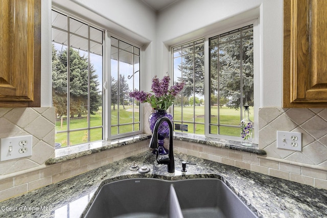 3025 N Sand Trap Way, Post Falls, ID 83854 - kitchen view of brown cabinetry, dark stone countertops, a sink, and tasteful backsplash