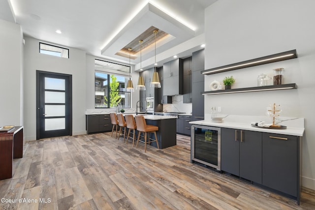 2888 W Lumber Ln, Coeur Dalene, ID 83814 - kitchen with beverage cooler, open shelves, light countertops, a kitchen breakfast bar, and wood finished floors