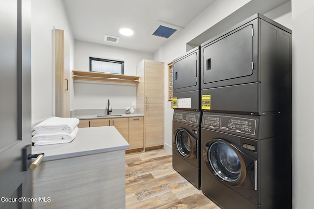 2888 W Lumber Ln, Coeur Dalene, ID 83814 - laundry room featuring stacked washer and clothes dryer, light wood-style floors, and cabinet space