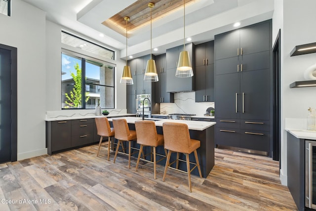 2888 W Lumber Ln, Coeur Dalene, ID 83814 - kitchen featuring a tray ceiling, modern cabinets, light wood finished floors, a kitchen breakfast bar, and decorative backsplash