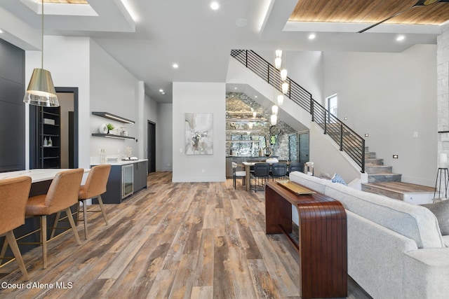 2888 W Lumber Ln, Coeur Dalene, ID 83814 - living room with wood finished floors, a towering ceiling, bar with sink, stairway, and recessed lighting