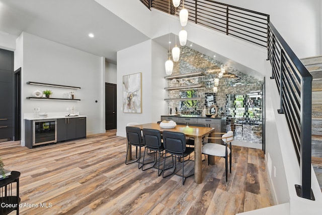 2888 W Lumber Ln, Coeur Dalene, ID 83814 - dining room featuring wet bar, beverage cooler, a towering ceiling, stairs, and light wood-style floors