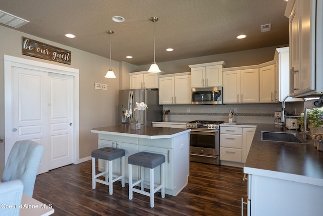 3423 E Hope Ave, Post Falls, ID 83854 - kitchen with appliances with stainless steel finishes, a sink, dark wood-style floors, tasteful backsplash, and a kitchen island