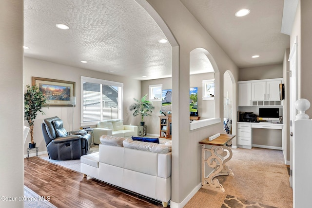 3423 E Hope Ave, Post Falls, ID 83854 - living area featuring arched walkways, recessed lighting, a textured ceiling, baseboards, and light colored carpet