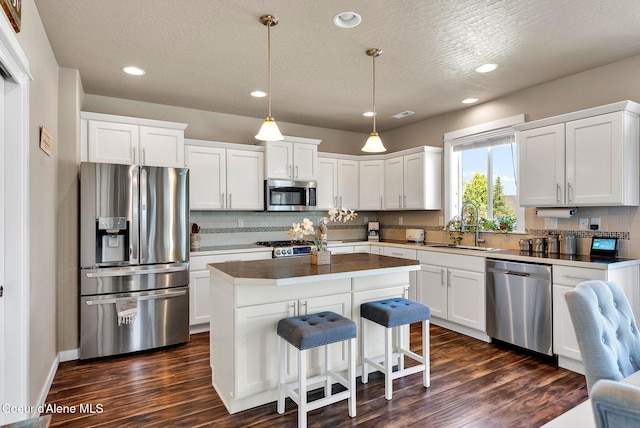 3423 E Hope Ave, Post Falls, ID 83854 - kitchen featuring stainless steel appliances, a sink, decorative backsplash, a kitchen island, and white cabinets
