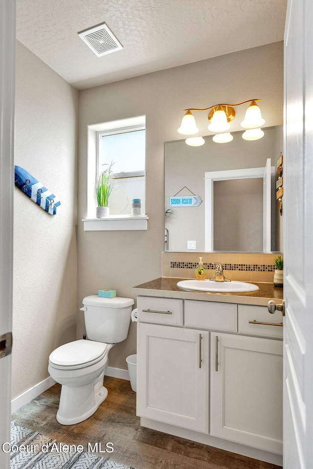 3423 E Hope Ave, Post Falls, ID 83854 - half bathroom with toilet, vanity, baseboards, wood finished floors, and a textured ceiling