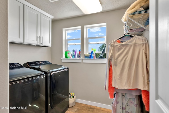3423 E Hope Ave, Post Falls, ID 83854 - laundry room featuring washer and clothes dryer, cabinet space, light wood-style flooring, baseboards, and a textured ceiling