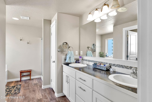 3423 E Hope Ave, Post Falls, ID 83854 - full bath with a textured ceiling, double vanity, wood finished floors, baseboards, and tasteful backsplash