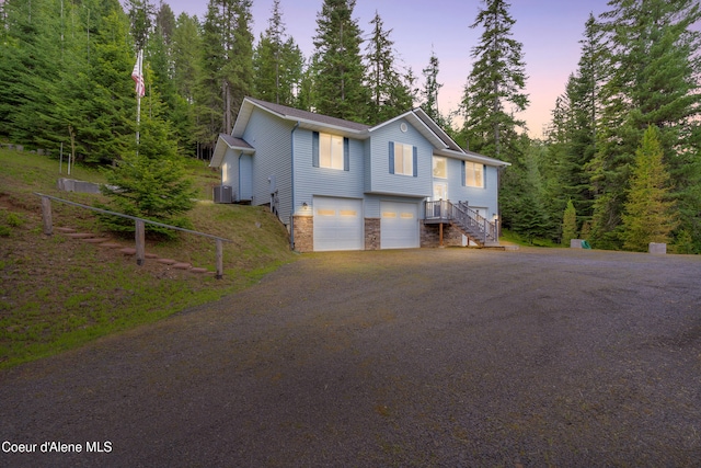 5340 W Hull Loop, Coeur Dalene, ID 83814 - view of front of home featuring a garage, central air condition unit, stone siding, and driveway
