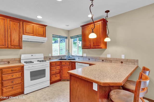 5340 W Hull Loop, Coeur Dalene, ID 83814 - kitchen with white appliances, under cabinet range hood, a peninsula, brown cabinetry, and recessed lighting