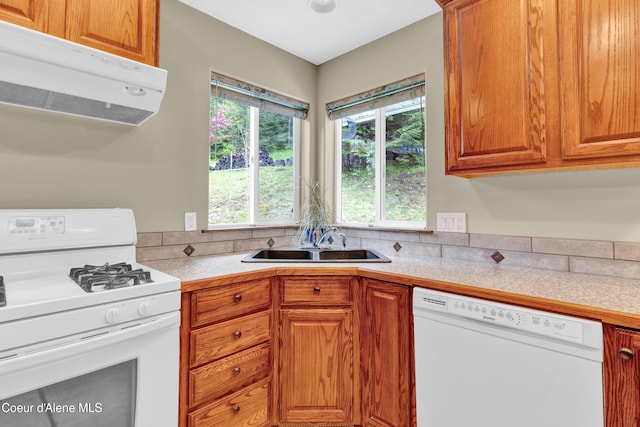 5340 W Hull Loop, Coeur Dalene, ID 83814 - kitchen with white appliances, under cabinet range hood, a sink, light countertops, and brown cabinetry