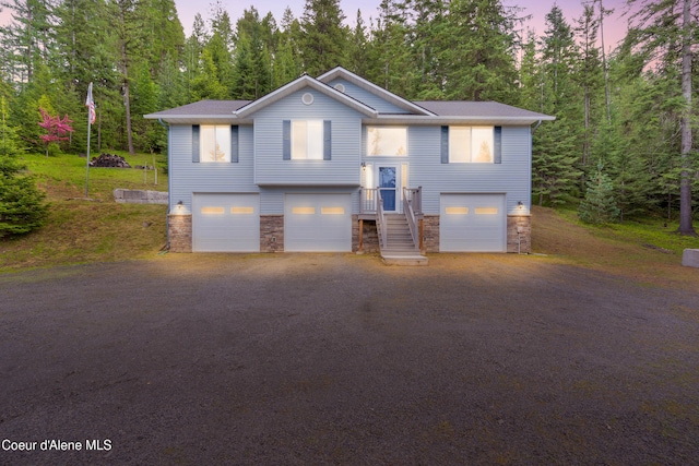5340 W Hull Loop, Coeur Dalene, ID 83814 - split foyer home featuring stone siding, a garage, and view of scattered trees