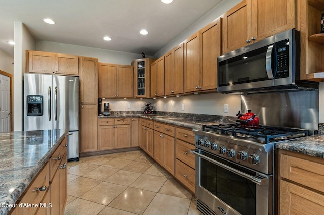 88 Fenway Dr, Sagle, ID 83860 - kitchen with appliances with stainless steel finishes, light tile patterned floors, glass insert cabinets, dark stone countertops, and recessed lighting
