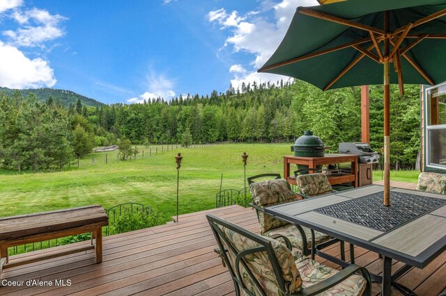 88 Fenway Dr, Sagle, ID 83860 - wooden deck featuring a forest view, a yard, grilling area, and outdoor dining area