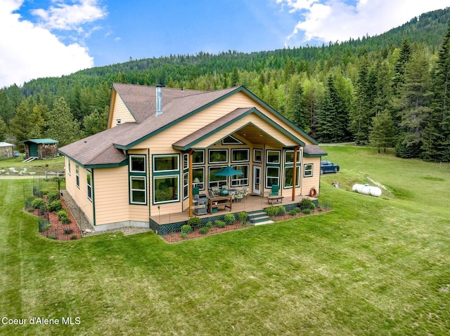 88 Fenway Dr, Sagle, ID 83860 - back of house featuring a wooded view, a yard, a shingled roof, and a patio