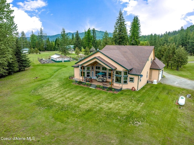 88 Fenway Dr, Sagle, ID 83860 - rear view of house with a mountain view, a lawn, driveway, and a forest view