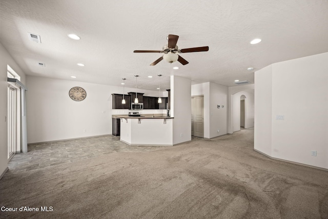 4717 N Connery Loop, Post Falls, ID 83854 - unfurnished living room featuring light colored carpet, arched walkways, ceiling fan, and recessed lighting