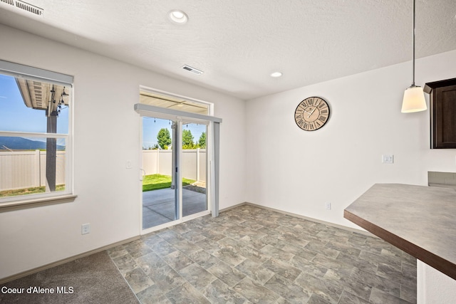 4717 N Connery Loop, Post Falls, ID 83854 - unfurnished dining area featuring stone finish flooring, recessed lighting, and a textured ceiling