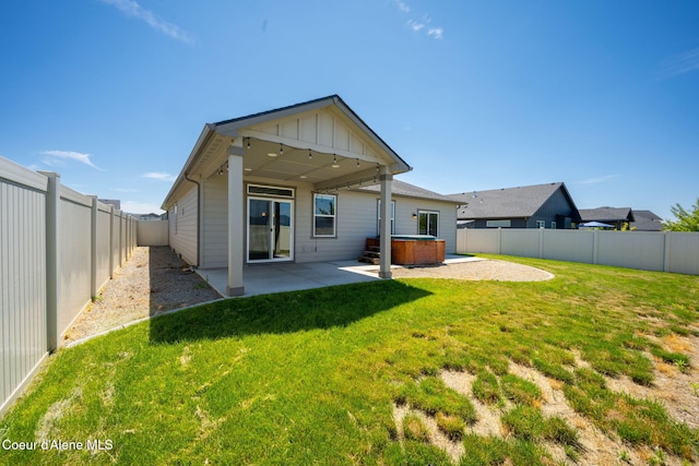 4717 N Connery Loop, Post Falls, ID 83854 - rear view of house with a hot tub, a patio, a fenced backyard, and board and batten siding
