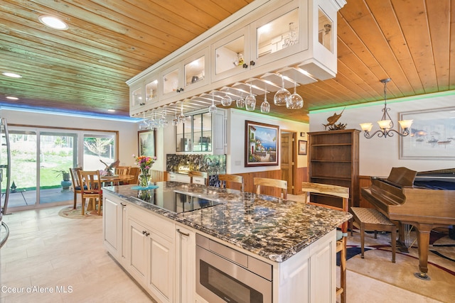471 Kaniksu Shores Rd, Sandpoint, ID 83864 - kitchen with black electric stovetop, wood ceiling, stainless steel microwave, dark stone counters, and decorative light fixtures