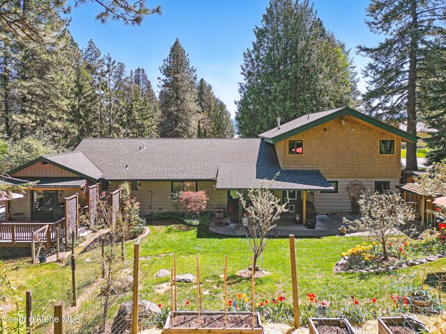 471 Kaniksu Shores Rd, Sandpoint, ID 83864 - back of house with a vegetable garden, a shingled roof, a lawn, and a patio