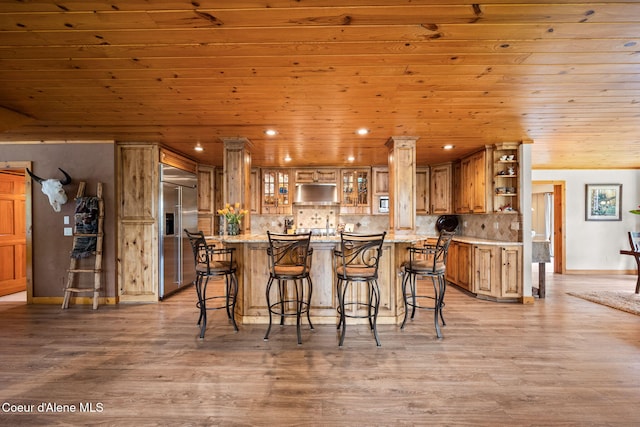 6918 E Garwood Rd, Hayden, ID 83835 - kitchen with stainless steel built in fridge, open shelves, wooden ceiling, brown cabinetry, and a kitchen bar