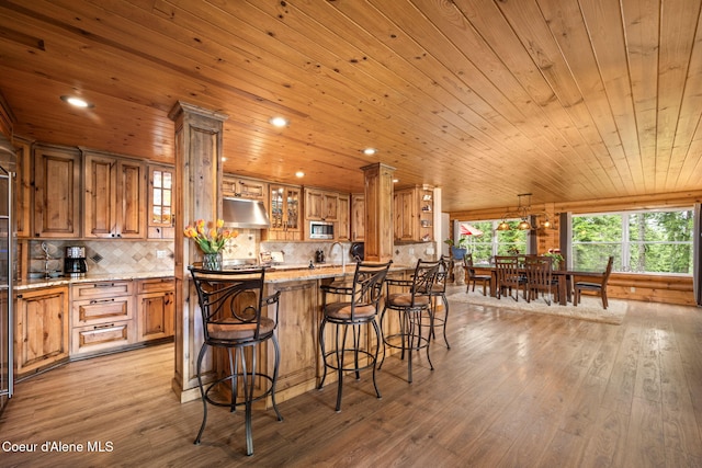 6918 E Garwood Rd, Hayden, ID 83835 - kitchen featuring wooden ceiling, under cabinet range hood, light wood-type flooring, brown cabinetry, and a breakfast bar