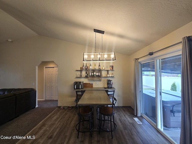 10566 N Seaside St, Hayden, ID 83835 - dining area featuring vaulted ceiling, arched walkways, dark wood finished floors, a dry bar, and baseboards