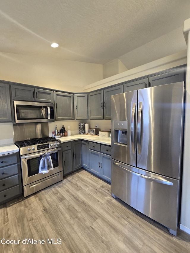 10566 N Seaside St, Hayden, ID 83835 - kitchen with appliances with stainless steel finishes, light countertops, light wood-type flooring, vaulted ceiling, and gray cabinets