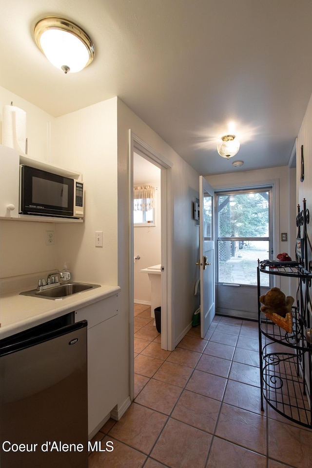 97 S Granite Bay Rd, Nordman, ID 83848 - kitchen with fridge, light tile patterned floors, a sink, white cabinets, and light countertops