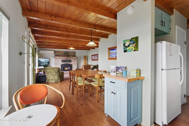 521 Aspen, Hope, ID 83836 - kitchen featuring freestanding refrigerator, wood finished floors, wooden ceiling with exposed beams, a fireplace, and hanging light fixtures