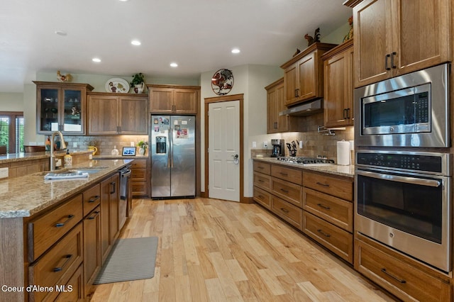 2795 Boekel Rd, Rathdrum, ID 83858 - kitchen with stainless steel appliances, a sink, under cabinet range hood, brown cabinetry, and recessed lighting