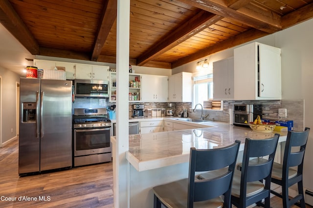 919 Silver Springs Rd, Moyie Springs, ID 83845 - kitchen featuring stainless steel appliances, a sink, wooden ceiling with exposed beams, tasteful backsplash, and light wood finished floors