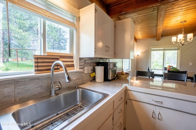919 Silver Springs Rd, Moyie Springs, ID 83845 - kitchen with a sink, light countertops, a chandelier, wooden ceiling with exposed beams, and backsplash