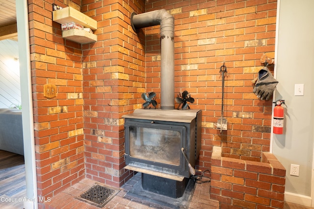 919 Silver Springs Rd, Moyie Springs, ID 83845 - detailed view of a wood stove, a fire extinguisher, baseboards, and wood finished floors