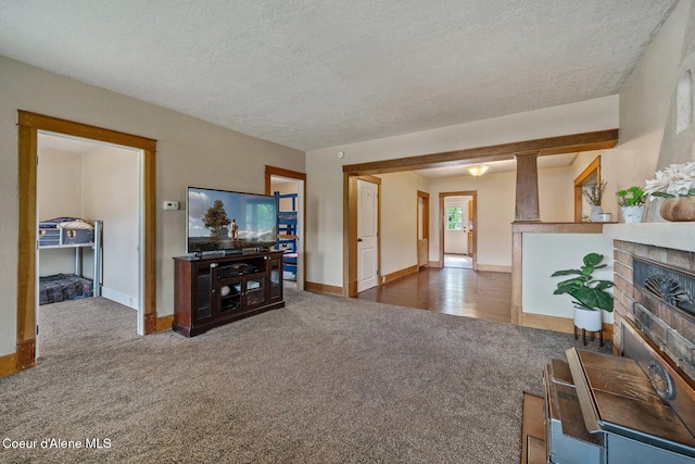 112 Washington St, Priest River, ID 83856 - living room featuring carpet, baseboards, a glass covered fireplace, and a textured ceiling