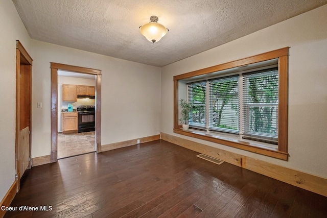 112 Washington St, Priest River, ID 83856 - spare room featuring a textured ceiling, dark wood-type flooring, and baseboards