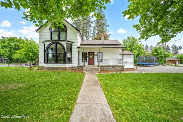 15152 N Mill St, Rathdrum, ID 83858 - view of front of home with a trampoline, a front yard, covered porch, and a chimney