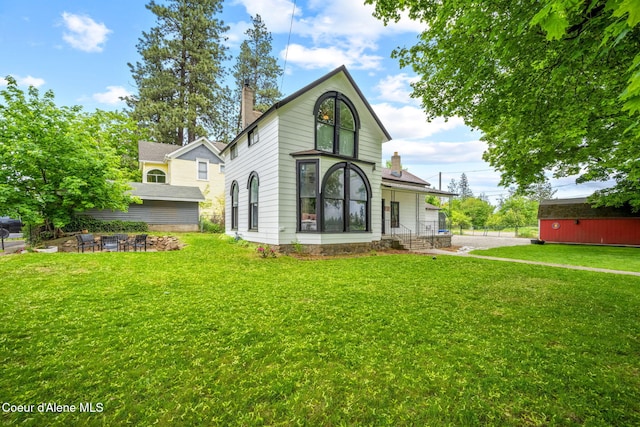 15152 N Mill St, Rathdrum, ID 83858 - rear view of house featuring a chimney, a lawn, and a fire pit