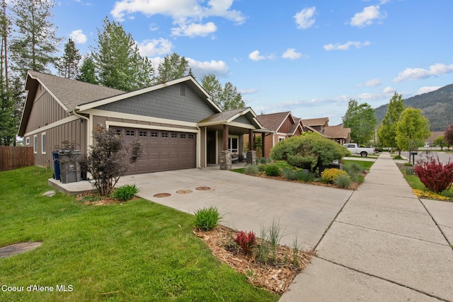 305 Maddie Ln, Sandpoint, ID 83864 - craftsman-style home with an attached garage, concrete driveway, board and batten siding, roof with shingles, and covered porch