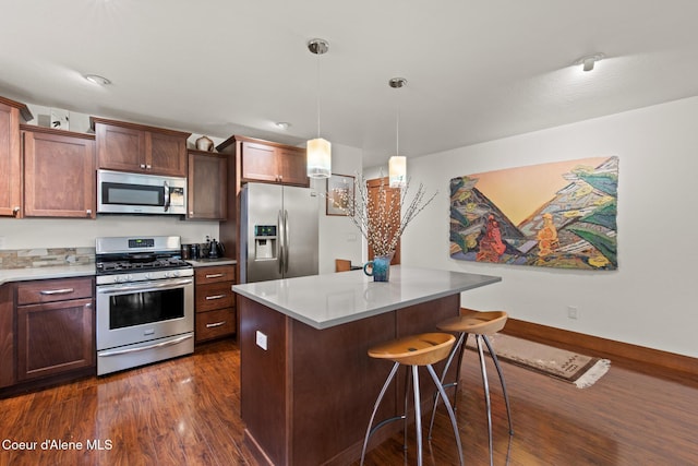 305 Maddie Ln, Sandpoint, ID 83864 - kitchen with appliances with stainless steel finishes, dark wood-style floors, a kitchen breakfast bar, pendant lighting, and a center island