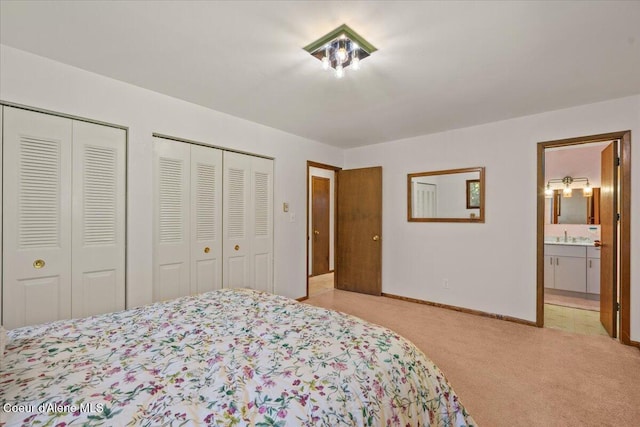 12696 N Dover Ln, Hayden, ID 83835 - bedroom featuring multiple closets, light carpet, ensuite bathroom, baseboards, and a sink