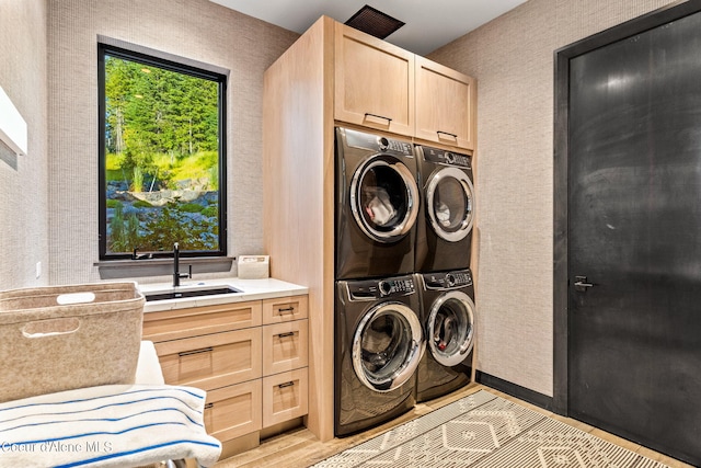 6361 S Cormorant Ct, Harrison, ID 83833 - laundry area featuring cabinet space, wallpapered walls, washer and clothes dryer, stacked washing machine and dryer, and light wood-type flooring